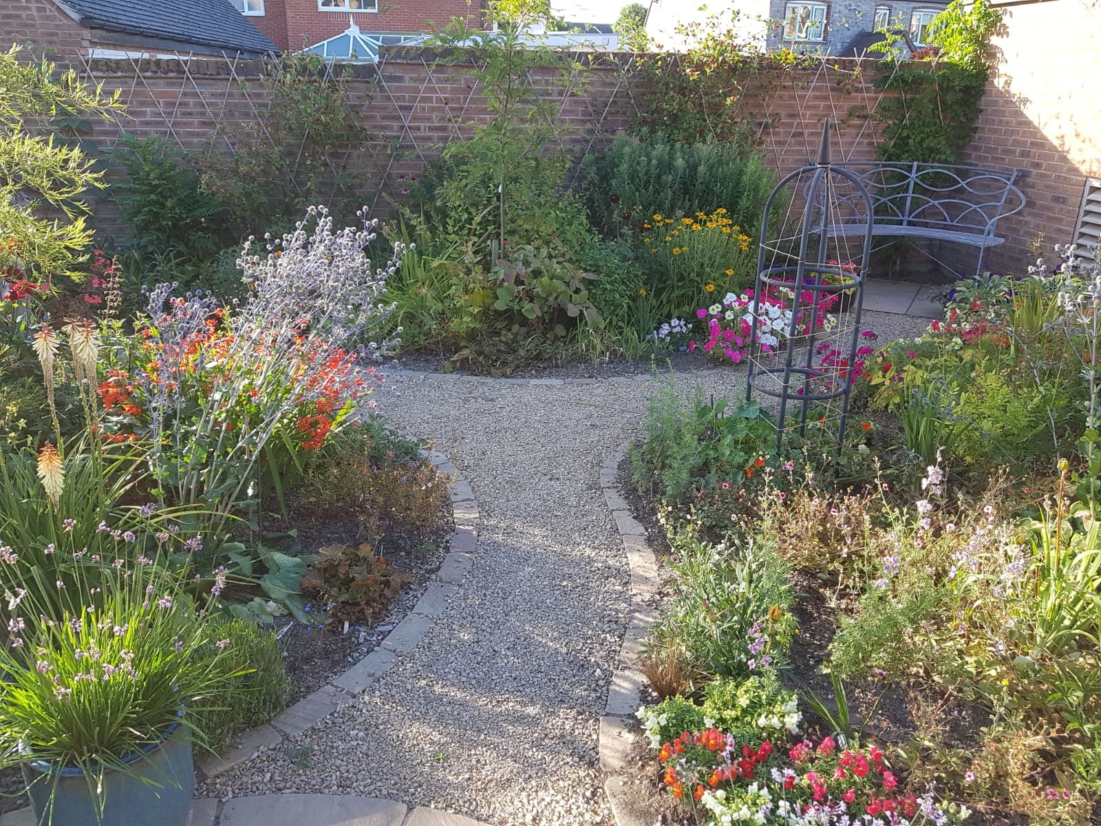 Lush cottage garden with colourful planting and gravel path