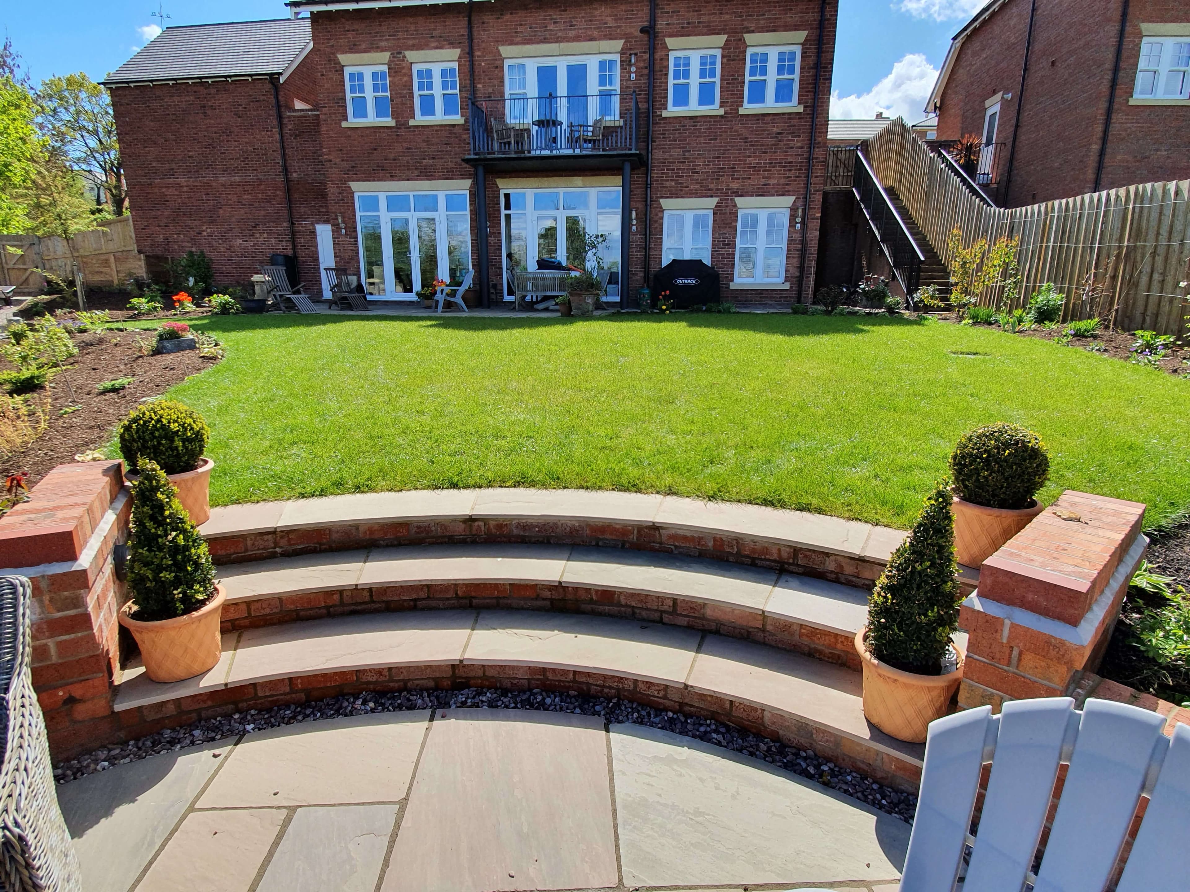 Curved patio steps with lawn and topiary planters