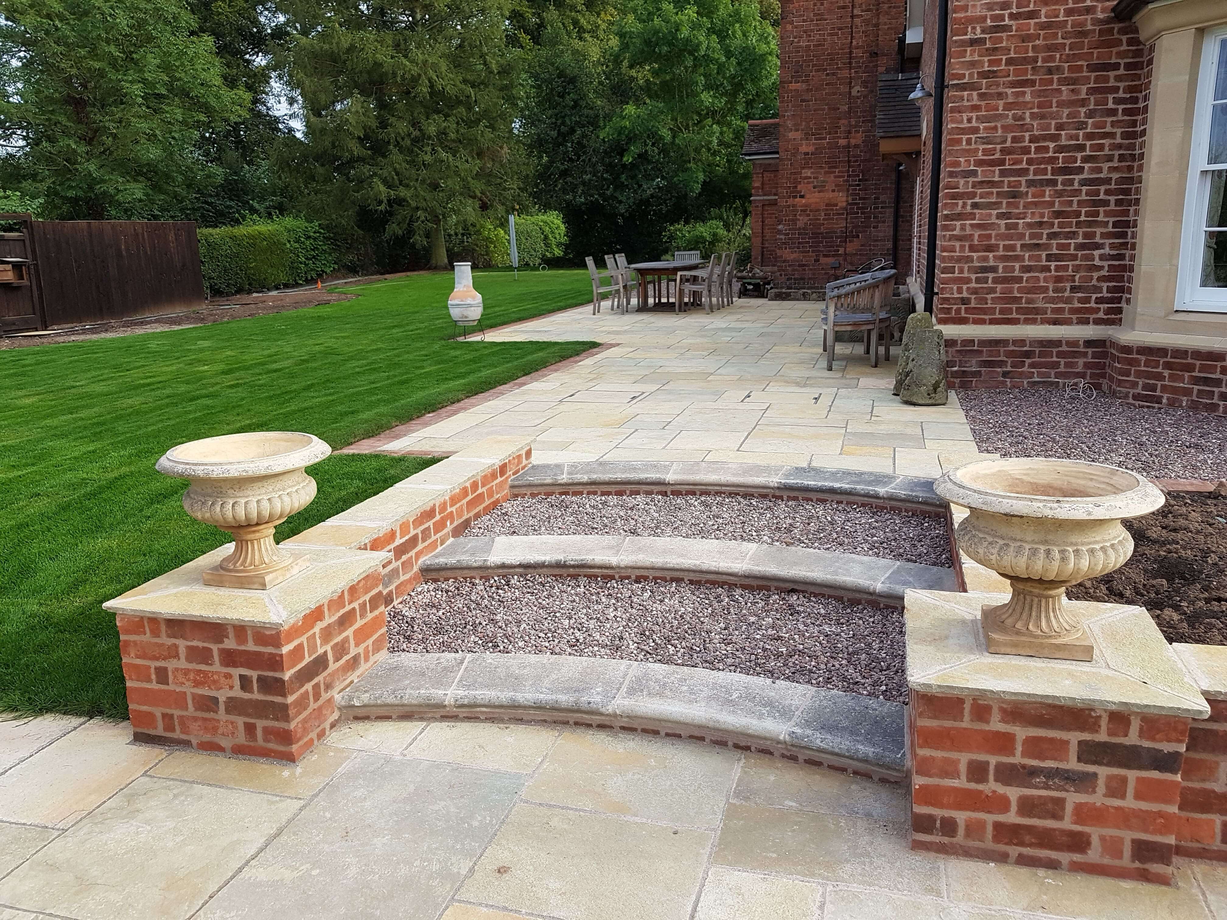 Elegant patio with curved stone steps and manicured lawn